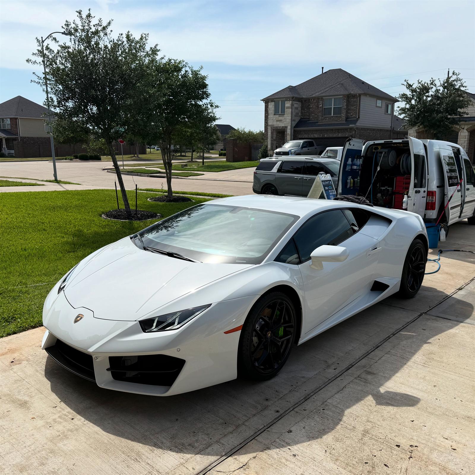 White Lamborghini Huracan being detailed on a residential driveway with the Glowtek Auto Care mobile detailing van parked behind it